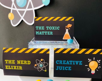 May include: Three black and yellow warning sign labels with white text. The top label reads "The Toxic Matter" with a beaker and orange liquid. The middle label reads "The Nerd Elixir" with an atom symbol. The bottom label reads "Creative Juice" with a light bulb.