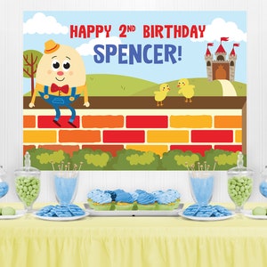 Puede incluir: Una mesa de decoraci&oacute;n para una fiesta de cumplea&ntilde;os con un esquema de color azul y verde. El tel&oacute;n de fondo presenta un personaje de dibujos animados, un castillo y el texto "Happy 2nd Birthday Spencer!"