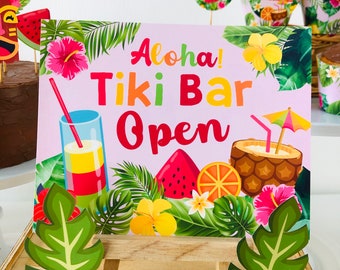 May include: A pink and green sign with the text "Aloha! Tiki Bar Open" surrounded by tropical leaves, flowers, and fruit. The sign is on a wooden easel.