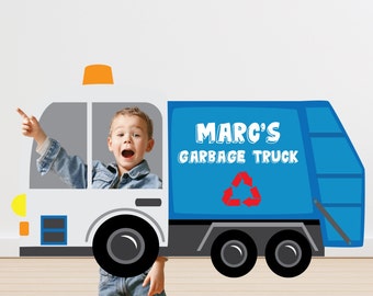 May include: A blue and white cardboard cutout of a garbage truck with the words "Marc's Garbage Truck" and a red recycling symbol. A child is peeking out of the driver's side window.