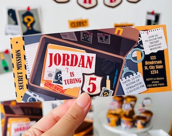 May include: A colorful invitation for a 5th birthday party with a detective theme. The invitation features a cartoon image of a briefcase with a magnifying glass, handcuffs, and a badge. The text on the invitation reads "Join us to solve the secret birthday mission!" and includes the date, time, and location of the party.