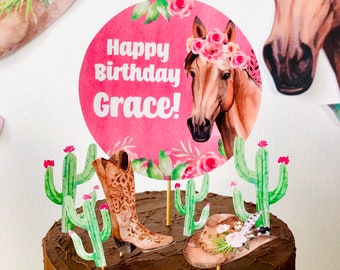 May include: A pink and green cake topper with a horse, cowboy boots, a hat, and cacti. The topper says "Happy Birthday Grace!"