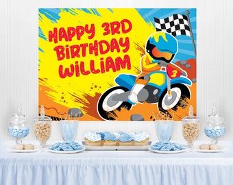 May include: A colorful birthday party backdrop with the text "HAPPY 3RD BIRTHDAY WILLIAM" and a cartoon illustration of a motocross racer on a blue motorcycle. The background is yellow, orange, and blue. A checkered flag waves in the background.