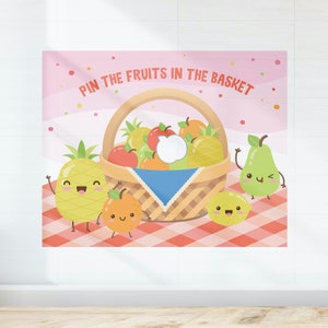 May include: A pink and white background with a basket of fruit and a red and white checkered tablecloth. The text "Pin the Fruits in the Basket" is at the top of the image. There are four cartoon fruits: a pineapple, an orange, a lemon, and a pear.
