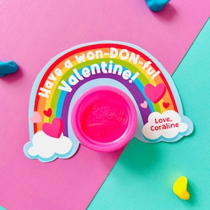 Può includere: Un biglietto di San Valentino con un design arcobaleno e la scritta "Have a won-DON-ful Valentine!". Un contenitore rosa di Play-Doh è posto sulla carta. La carta include anche cuori e la scritta "Love, Coraline."