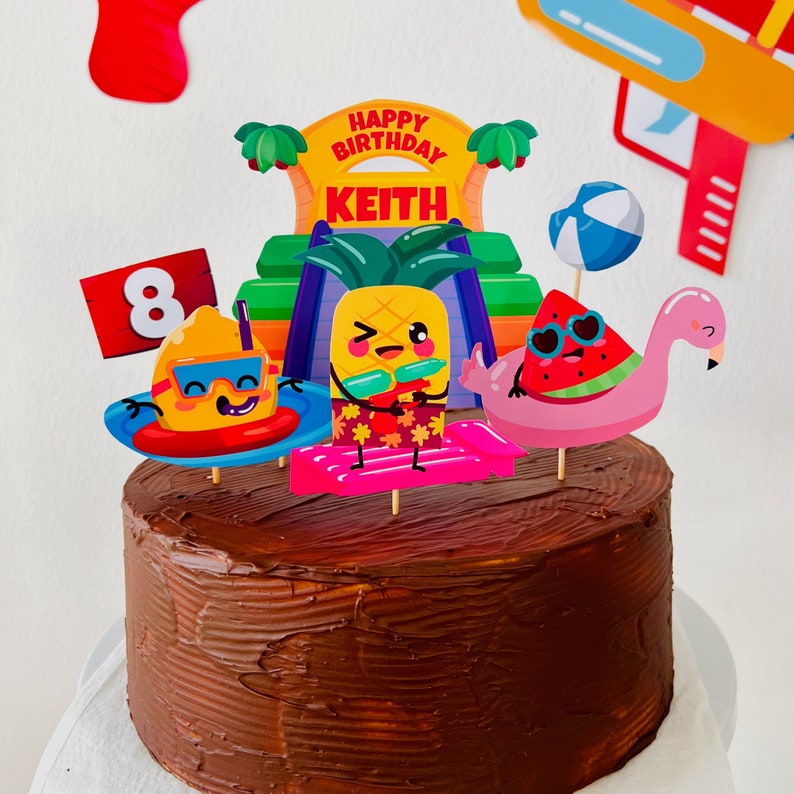 May include: A chocolate cake decorated with a summer-themed party scene. The cake is topped with a sign that says "Happy Birthday Keith" and a number 8. There are also several other decorations, including a pineapple, a watermelon, a flamingo, and a beach ball.