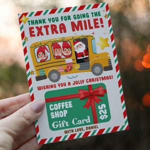 Könnte beinhalten: Eine weihnachtliche Geschenkkarte mit einem gelben Schulbus, der Elfen und den Weihnachtsmann transportiert. Die Karte trägt die Aufschrift "THANK YOU FOR GOING THE EXTRA MILE!" und "WISHING YOU A JOLLY CHRISTMAS!". Eine grüne Geschenkkarte für ein Café ist ebenfalls abgebildet.