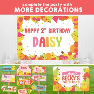 Colourful fruit-themed party decorations for a 2nd birthday party. The decorations include a large banner with the text "Happy 2nd Birthday Daisy", several signs with fruit-themed designs and text, and a photo booth backdrop. The signs include text such as "Party Like a Pineapple", "Fruit Stand", "Let's Go Banana", and "Welcome to Becky's Twotti-Frutti".