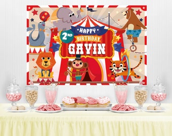 May include: A red and white circus themed party backdrop with a banner that says "Happy 2nd Birthday Gavin". The backdrop features a variety of circus animals including a lion, tiger, monkey, elephant, and a bear riding a unicycle.