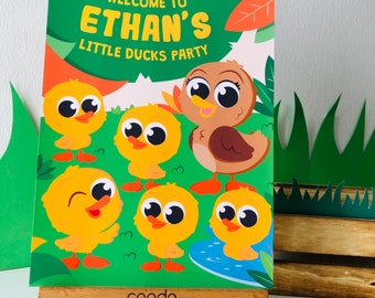 May include: A green and orange welcome sign with the text "Welcome to Ethan's Little Ducks Party". The sign features a brown duck and five yellow ducklings with big eyes.