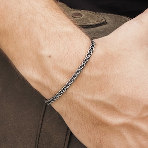 May include: A silver chain bracelet with a braided design.
