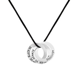 May include: Silver interlocking rings necklace with the inscription "Always in my heart 25. Nov. 96" on one ring and "x. Penelope" on the other ring. The necklace is on a black cord.