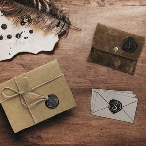 A beautiful picture displaying the packaging that the ring comes in is laid down on a wooden surface. A wrapped up box an envelope and a card along with the jewelry.