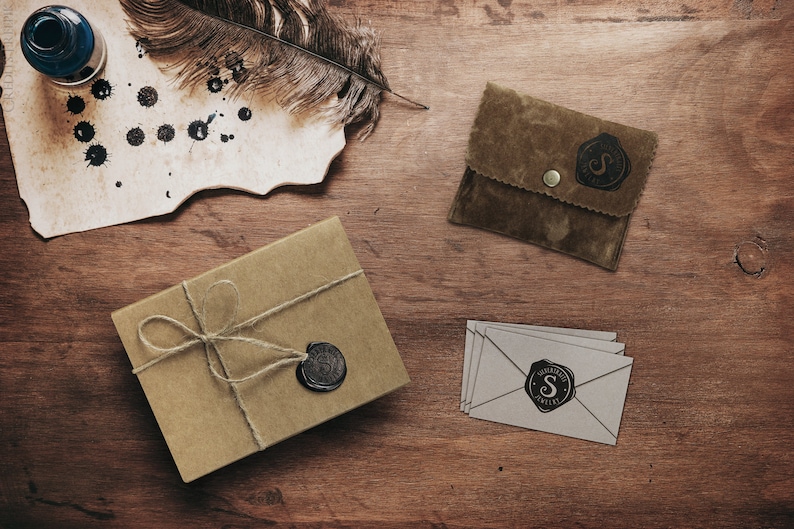 A beautiful picture displaying the packaging that the ring comes in is laid down on a wooden surface. A wrapped up box an envelope and a card along with the jewelry.