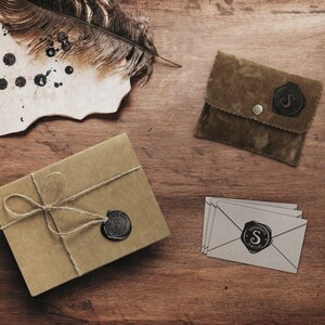 A beautiful picture displaying the packaging that the bracelet comes in is laid down on a wooden surface. A wrapped up box an envelope and a card along with the jewelry.