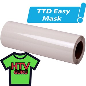 May include: A roll of white heat transfer vinyl with the text "TTD Easy Mask" on a blue label. The vinyl is used for creating custom designs on fabric.