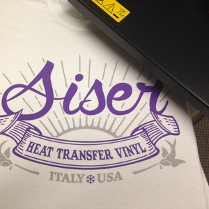 K&ouml;nnte beinhalten: Ein wei&szlig;es T-Shirt mit einem violetten Design, auf dem "Siser Heat Transfer Vinyl Italy USA" mit einem Schneeflocken-Symbol steht.