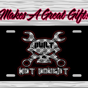 May include: Black license plate with a skull and crossed wrenches design. The word "BUILT" is above the skull, and "NOT BOUGHT" is below. The text "Makes A Great Gift!" is above the plate.