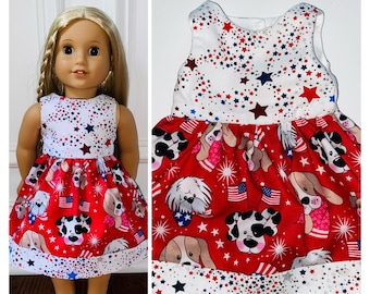 May include: A red and white sleeveless dress with a patriotic theme. The dress features a white bodice with blue and red stars and a red skirt with a pattern of dogs wearing red, white, and blue bandanas and holding American flags.