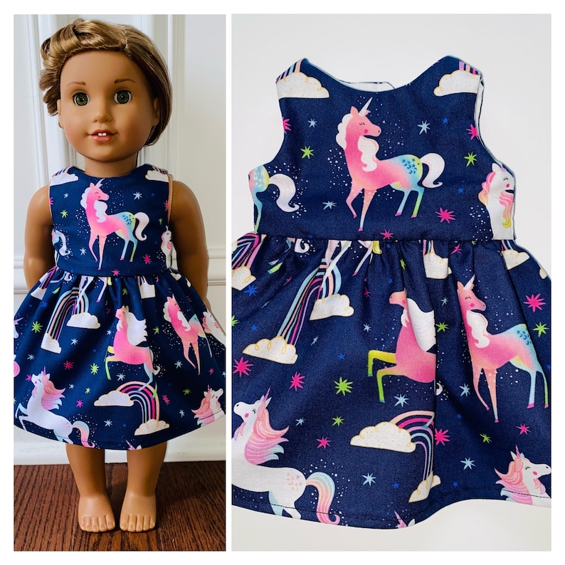 May include: A blue sleeveless dress with a unicorn print. The dress has a rainbow, cloud and star pattern. The dress is for a doll.