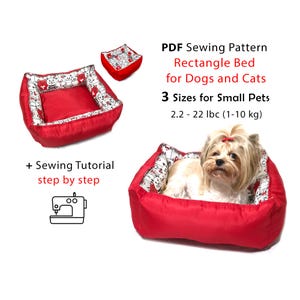Op de afbeelding: Rood rechthoekig dierenbed met een wit en zwart kattenpatroon. De afbeelding bevat een kleine hond in het bed, een kleinere versie van het bed en tekst met de tekst "PDF-naaipatroon Rechthoekig bed voor honden en katten."