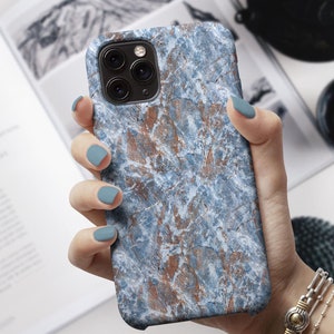 Può includere: Una custodia per telefono in marmo blu e marrone per un iPhone. La custodia ha una superficie testurizzata e un ritaglio per la fotocamera.