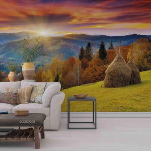May include: A living room with a sofa and a coffee table in front of a wall mural depicting a scenic landscape with a sunset over rolling hills and hay bales in a field.