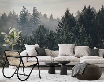 May include: A living room interior with a white sofa and a black wicker chair. The wall behind the furniture features a large-scale photo mural of a misty forest.