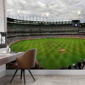 Könnte beinhalten: Panoramablick auf ein großes, grünes, im Freien liegendes Stadion mit einer Menschenmenge auf den Tribünen. Das Stadion ist von einem Zaun umgeben und auf dem Zaun befinden sich Lichter. Das Spielfeld ist leer, bis auf ein paar Personen in der Mitte des Spielfelds.