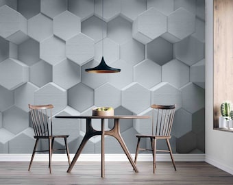 May include: A dining room with a round wooden table and two wooden chairs. The wall is covered in a 3D hexagonal pattern wallpaper in a light grey colour. A black pendant light hangs above the table.