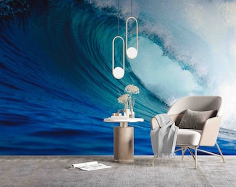 Puede incluir: Un diseño de interior de sala de estar con un gran mural de una ola oceánica en la pared. La habitación cuenta con un cómodo sillón con una manta, una mesa auxiliar con un jarrón de flores secas y dos lámparas colgantes modernas.