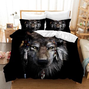 May include: Black and white wolf bedding set with a close-up image of a wolf's face with feathers and beads. The wolf's eyes are a bright yellow.