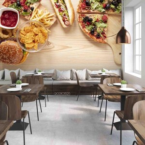 Könnte beinhalten: Eine Wandmalerei mit Holzmaserung, die ein Restaurant-Tischsetting mit einer Auswahl an Speisen zeigt, darunter Pizza, Hotdog, Hamburger, Pommes Frites, Zwiebelringe und eine Schüssel mit Chips. Der Tisch ist mit einem braunen Holztisch, Stühlen und einer braunen Pendelleuchte an der Decke gedeckt.