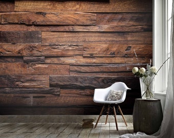 May include: A white chair with a light brown cushion sits in front of a wall covered in dark brown wood planks. A vase with white flowers sits on a dark gray side table.
