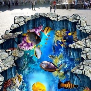 May include: A 3D floor decal featuring a realistic hole in a cobblestone street revealing an underwater coral reef scene. The vibrant display includes various tropical fish in shades of yellow, blue, and orange swimming among colorful coral formations.