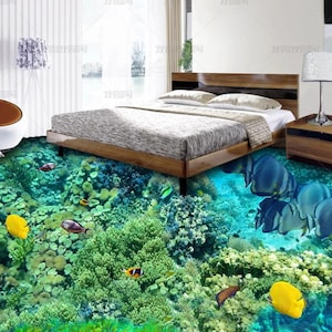 May include: A bedroom featuring a wooden bed frame with a gray mattress, a wooden nightstand with a silver lamp, and a white chair. The floor is covered in a 3D mural depicting a vibrant coral reef with various colorful fish swimming underwater.