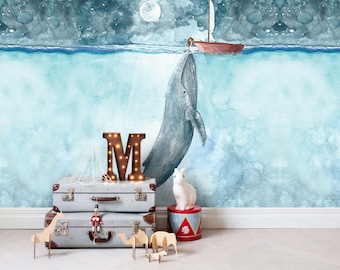 May include: Watercolor mural featuring a whale, sailboat, and a full moon in a night sky. Decorative suitcases, a light-up letter "M", and wooden animal figurines are in the foreground, creating a whimsical scene.