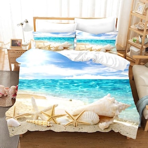 Może przedstawiać: Zestaw pościeli w kolorze białym i niebieskim z motywem plaży, z wzorem muszli i gwiazd morskich. Zestaw pościeli zawiera poszewkę na kołdrę, dwie poszewki na poduszki i prześcieradło.