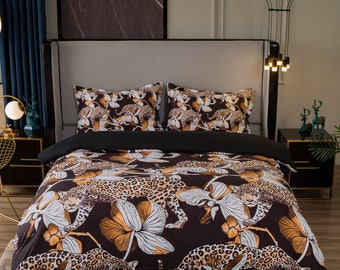 Puede incluir: Una funda nórdica negra y marrón con estampado de leopardo y diseño floral blanco. La funda nórdica está en una cama con dos fundas de almohada a juego.