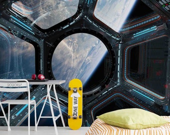 May include: A yellow skateboard with the words "One Way" printed on it, leaning against a white desk in front of a mural depicting a spaceship window with a view of Earth.