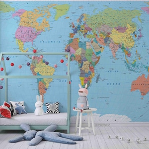 May include: A vibrant world map mural adorns a child's bedroom. A pale blue bed frame with a white mattress is positioned in front of the map. Decorative cushions, soft toys, and a garland of red and white baubles enhance the room's playful atmosphere.