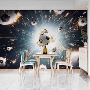 May include: A soccer-themed wall mural with a dynamic design. The image features multiple soccer balls amidst a burst of light and sparks. A small table and chairs are in the foreground, creating a dining scene. The color palette includes shades of blue, white, and brown.