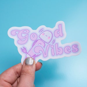 May include: A white sticker with a purple cartoon character holding a plug and the text "Good Vibes" in purple.