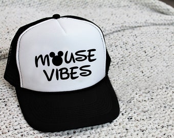May include: A white and black trucker hat with a black mouse head and the text "MOUSE VIBES" in black.