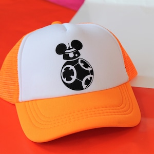 Może przedstawiać: Biało-pomarańczowa czapka trucker z czarno-białym obrazkiem droida BB-8 z Gwiezdnych Wojen z uszami Myszki Miki na górze.