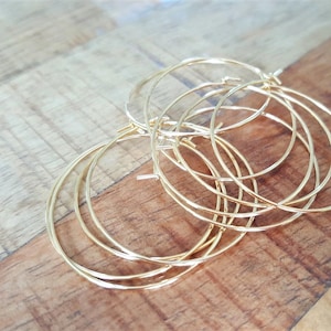 May include: A set of five gold hoop earrings of varying sizes. The hoops are stacked on top of each other, creating a layered effect.