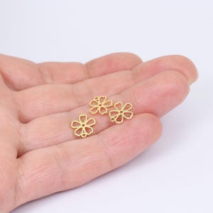 May include: Three gold-colored metal flower charms with a delicate, intricate design. The charms are small and perfect for adding a touch of elegance to jewelry projects.