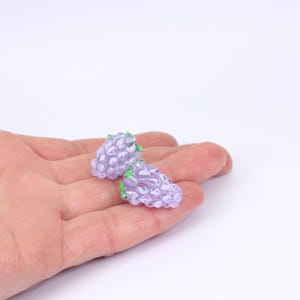 May include: Two purple glass berry charms with green leaves. The charms are small and detailed, resembling real berries.