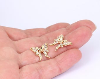 May include: Two gold-toned butterfly-shaped charms featuring clear, faceted stones embedded along the wings. Each butterfly has a symmetrical design with delicate, curved antennae and detailed wing segments, showcasing a polished metallic finish.