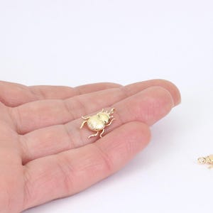 May include: A gold-colored beetle charm pendant. The charm is detailed and has a textured surface.